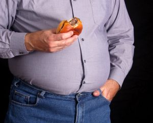 overweight man eating cheeseburger