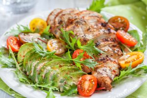 Healthy salad plate with colorful tomatoes, chicken breast and avocado