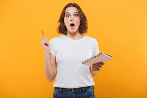 Excited young woman writing notes. Looking camera have an idea.