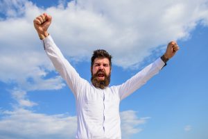Feel free. Guy emotional shout face proud of himself. Full of energy. Man bearded hipster feels powerful and full of energy when reached top achievement. Man emotional enjoy freedom sky background