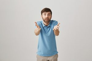 Impressed excited european worker gesturing towards camera as if talking about person, being amazed and happy while standing over gray background. Guy congratulate friend that did something great