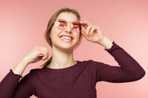 Woman smiling with perfect smile and white teeth on the pink studio background