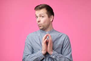 Tricky mature man thinking looking with hand together over pink background.