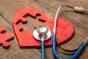 Heart puzzle red and stethoscope on wooden background. Concept d