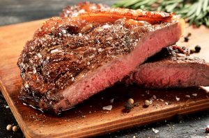 Rare New York strip steak on wooden board, selected focus