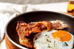 Frying pan with fried egg and bacon, closeup