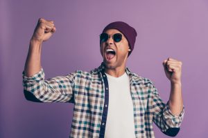 Close up photo portrait of mad excited ecstatic rejoicing handsome attractive people person holding raising hands fists up screaming hooray isolated violet background