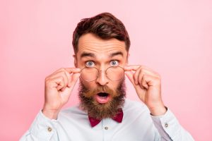 Close-up photo of shocked expressing bright reaction person in formal apparel touching eyewear isolated pastel background
