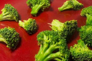 Green Brocolli on Red Plate on White Background