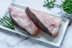 Two raw halibut steaks garnished with samphire - top view